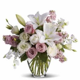 Bouquet of white lilies and pink roses in a clear glass vase