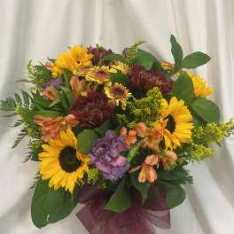 Mixed bouquet with sunflowers, chrysanthemums, and alstroemeria in a glass vase