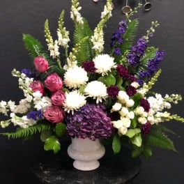 Large mixed floral arrangement in a white pedestal vase