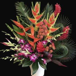 Tropical bouquet with orange heliconia and purple orchids in a white vase