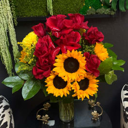 Bouquet of red roses and yellow sunflowers in a glass vase