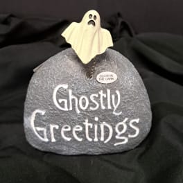Ghost figurine on a gray stone with "Ghostly Greetings" text