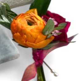 Orange and magenta ranunculus bouquet with green leaves