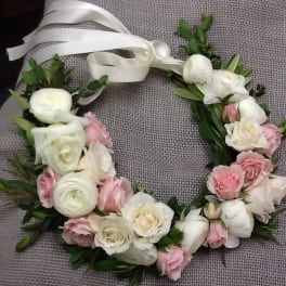 Floral wreath with white and pink roses tied with a white ribbon