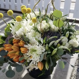 Bouquet of white chrysanthemums and orange tulips in a dark vase