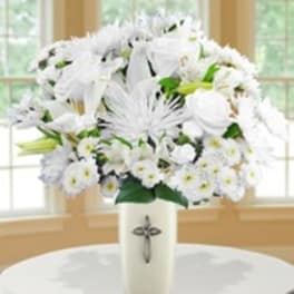 White floral arrangement in a tall vase with a cross emblem