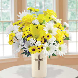Yellow and white flower arrangement in a cream vase with a cross