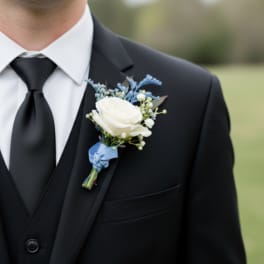White rose boutonniere with blue accents pinned to a black suit lapel