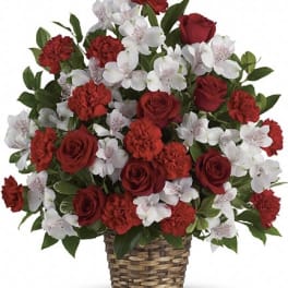 Red roses and carnations with white orchids in a woven basket