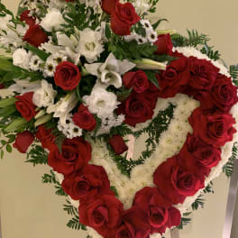 Heart-shaped red and white floral standing arrangement on an easel