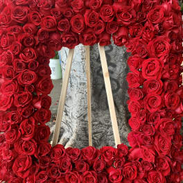 Large rectangular floral wreath of red roses on a wooden easel