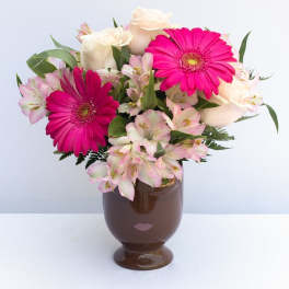 Pink gerbera daisies and white roses in a brown vase