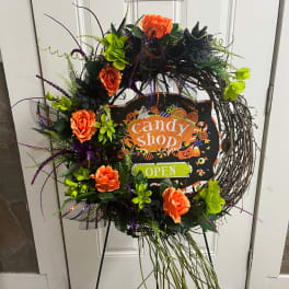 Halloween wreath with orange flowers and a candy shop sign