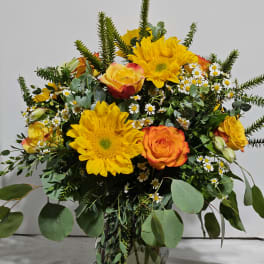 Bouquet of yellow sunflowers and orange roses in a glass vase