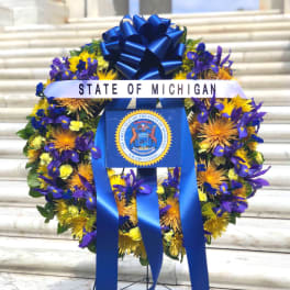 Blue and white memorial wreath with a ribbon and state seal