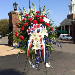 Large standing floral spray with red, white, and blue flowers and ribbon