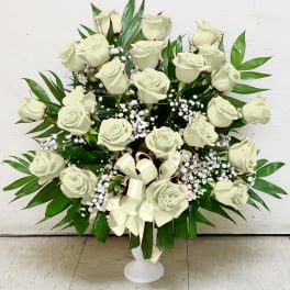 White rose funeral spray in a white pedestal vase