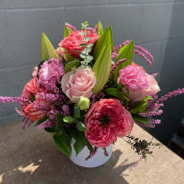 Pink roses and lilies arranged in a white vase