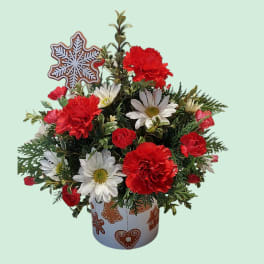 Red and white flowers in a decorated holiday pot with a snowflake topper