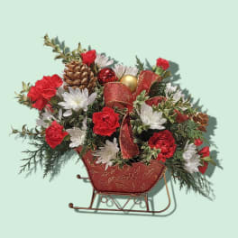Holiday floral arrangement in a sleigh-shaped container with red and white blooms