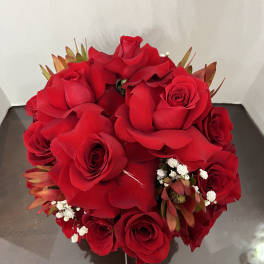 Round bouquet of red roses with small white filler flowers