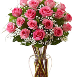 Bouquet of pink roses with white filler flowers arranged in a clear glass vase