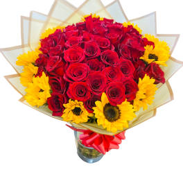 Bouquet of red roses and yellow sunflowers in a glass vase