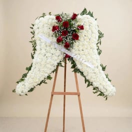 White floral funeral spray with red roses on a wooden easel