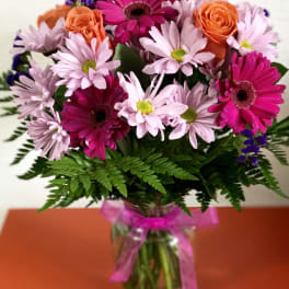 Bouquet of pink daisies and orange roses in a glass vase