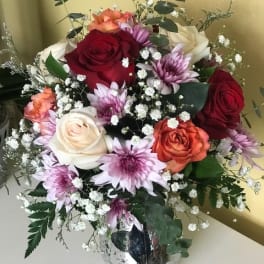Bouquet of roses and purple daisies in a clear glass vase