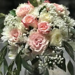 Bouquet of pink and white roses with baby's breath in a glass vase