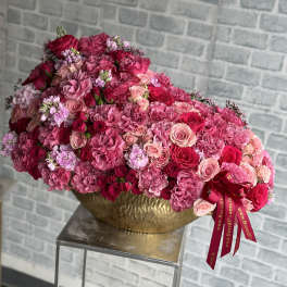 Large pink and red rose arrangement in a gold bowl