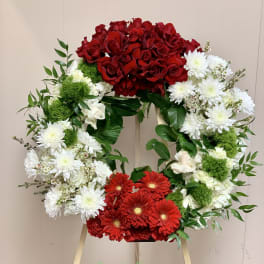 Heart-shaped floral wreath with red roses, white daisies, and red gerberas