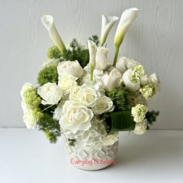 White roses and calla lilies arranged in a patterned vase