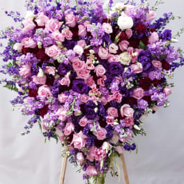 Heart-shaped bouquet of pink and purple flowers on a stand