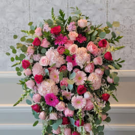 Large pink and red floral arrangement on an easel