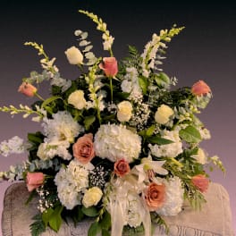 Large floral arrangement with white hydrangeas, roses, and lilies in soft pink and cream.