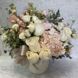 Cream roses and pink hydrangeas in a ribboned vase