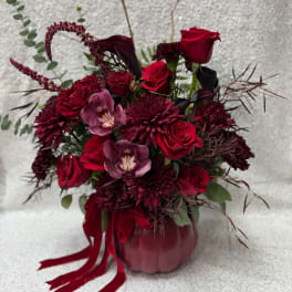 Red roses and burgundy flowers arranged in a pumpkin vase