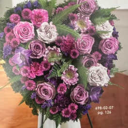 Heart-shaped bouquet of pink and purple flowers on a stand