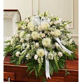 White funeral spray with lilies and roses on a casket
