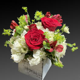 Red roses and white flowers in a rustic square container