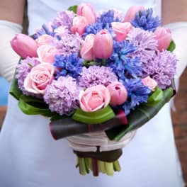 Pink tulips and roses with purple and blue flowers in a hand-tied bouquet
