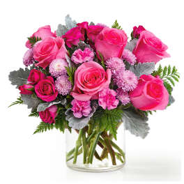 Pink roses and small lavender flowers in a clear glass vase