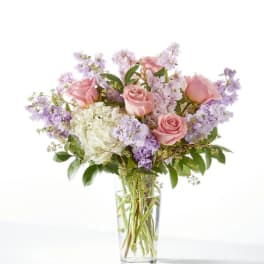Pink roses and lavender flowers in a clear glass vase