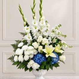 White floral arrangement with blue hydrangeas in a white vase