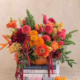 Colorful autumn bouquet in a pumpkin container with a small pumpkin beside it