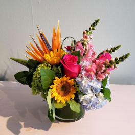 Mixed bouquet in a round vase with sunflower, roses, hydrangea, and snapdragons