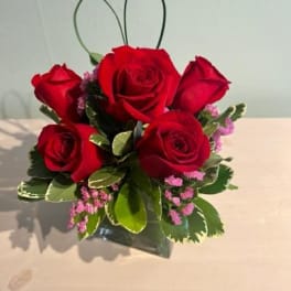 Small bouquet of red roses with pink filler flowers in a black container