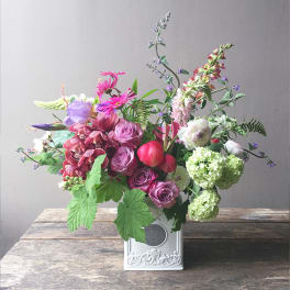 Mixed bouquet of pink, purple, and white flowers in a white vase